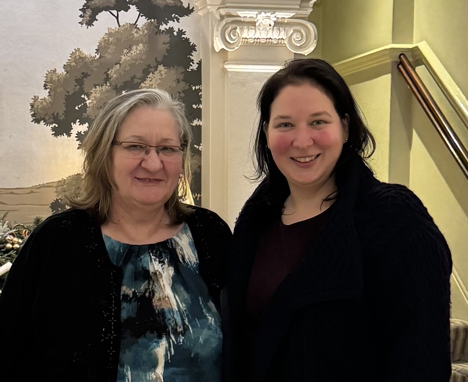 Szilvia Kocsy with her mum Piroska, photographed on a staircase in front of a painted landscape mural.